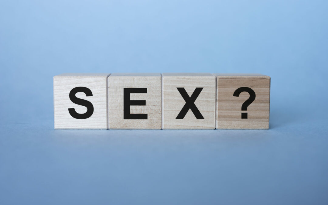Three wooden cubes with word SEX on table with question mark