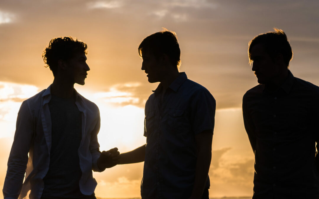 Silhouette of three young men at the beach at sunset